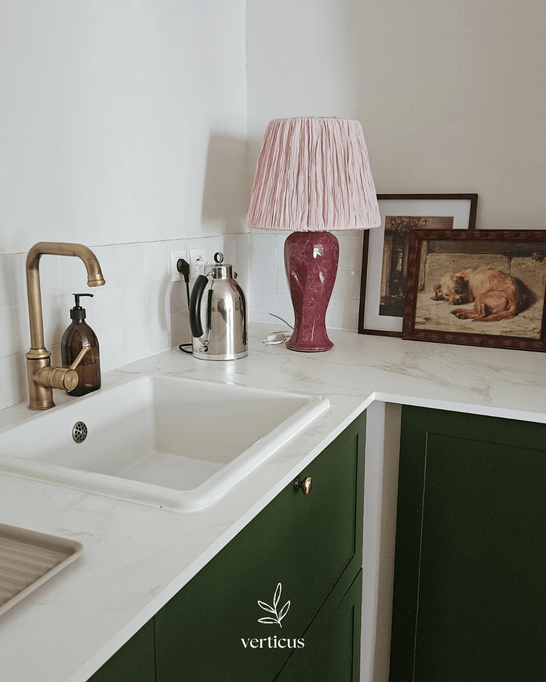 Cuisine verte avec petite lampe rose, cadres anciens et robinet en laiton