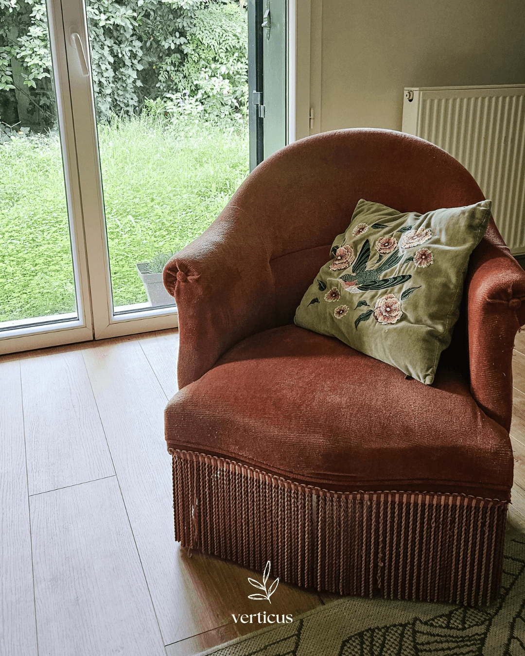 Fauteuil ancien rose à franges avec coussin botanique près du jardin